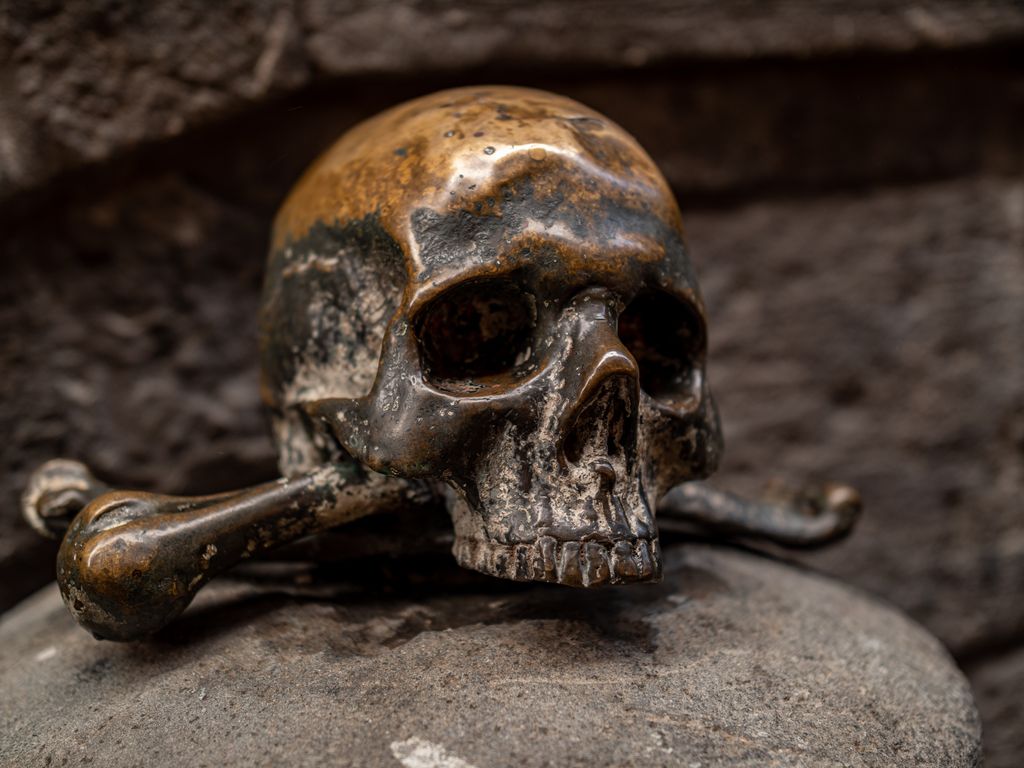 Close-up of a weathered skull and crossbones sculpture in Naples, Italy, capturing historic charm.